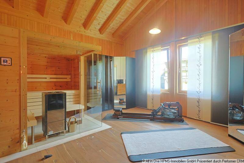 Privater Wellnessbereich mit Sauna, Fitnessgeräten und Holzboden unter Dachschrägen.