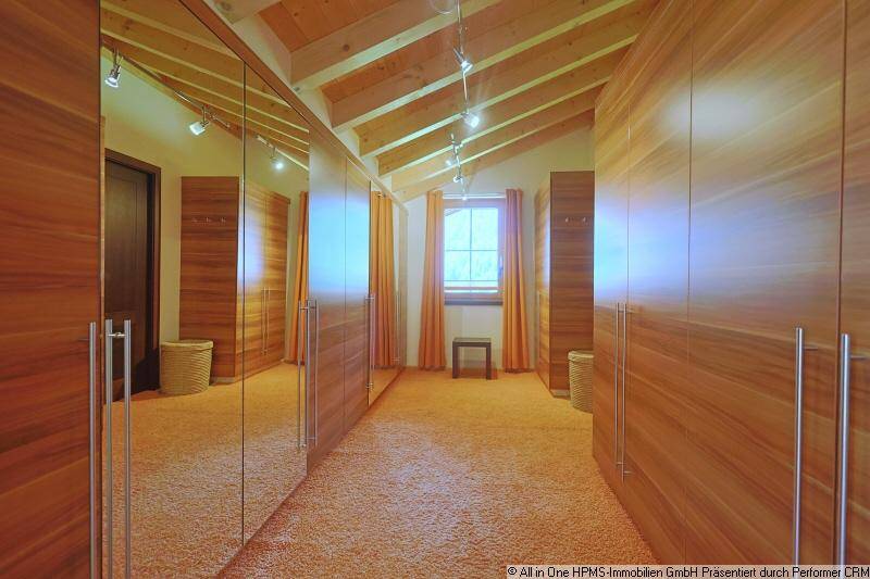 Geräumiger begehbarer Kleiderschrank mit Spiegeltüren, Teppichboden und Dachschrägen.