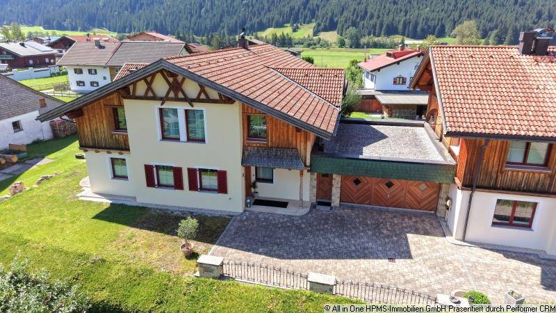 Vorderansicht des Hauses mit gepflasterter Auffahrt, Doppelgarage und traditionellen Fensterläden.