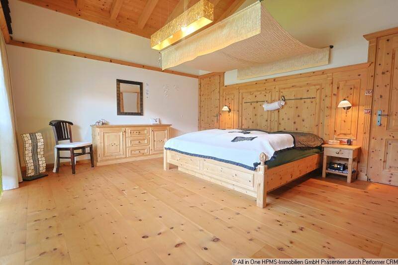 Gemütliches Schlafzimmer im alpenländischen Stil mit viel Holz, Holzboden und Einbauschränken.