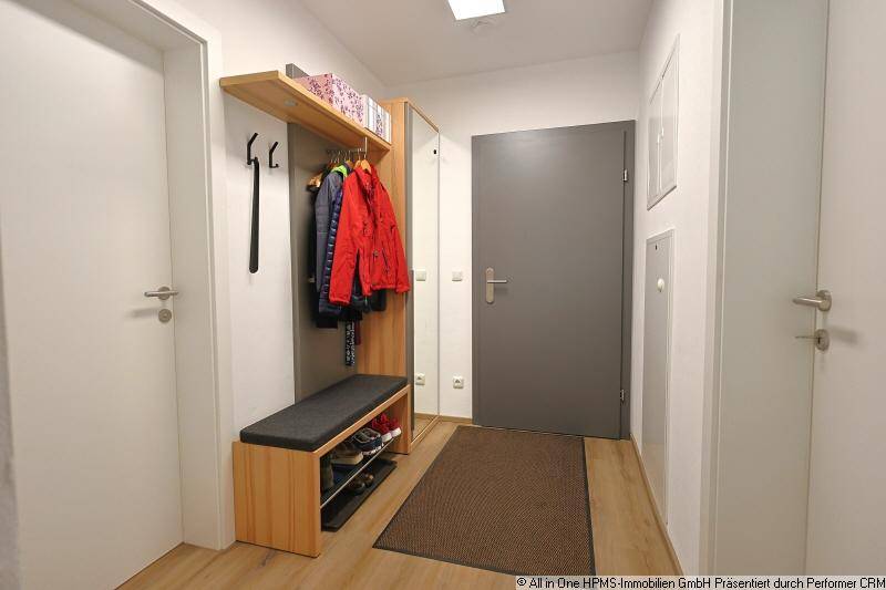 Heller Eingangsbereich mit Garderobe, Sitzbank und Spiegel für praktischen Stauraum.