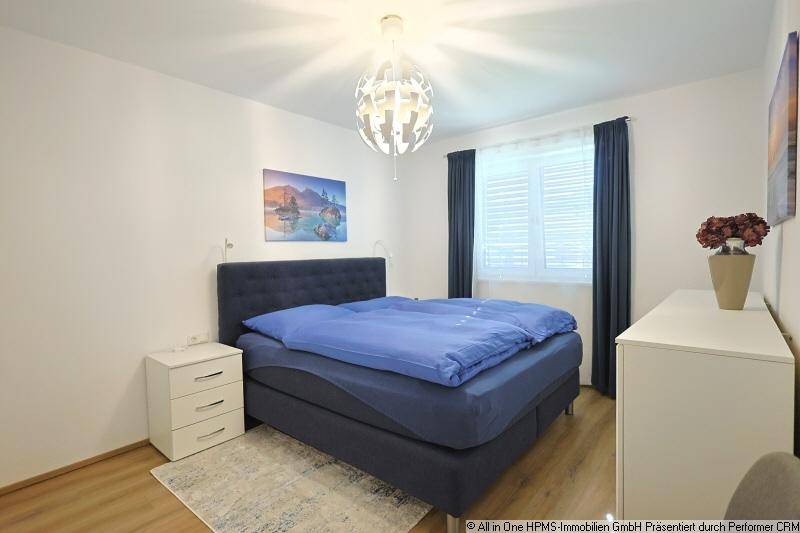 Helles Schlafzimmer mit bequemem Doppelbett, Nachttischen und einem Fenster mit Jalousien.