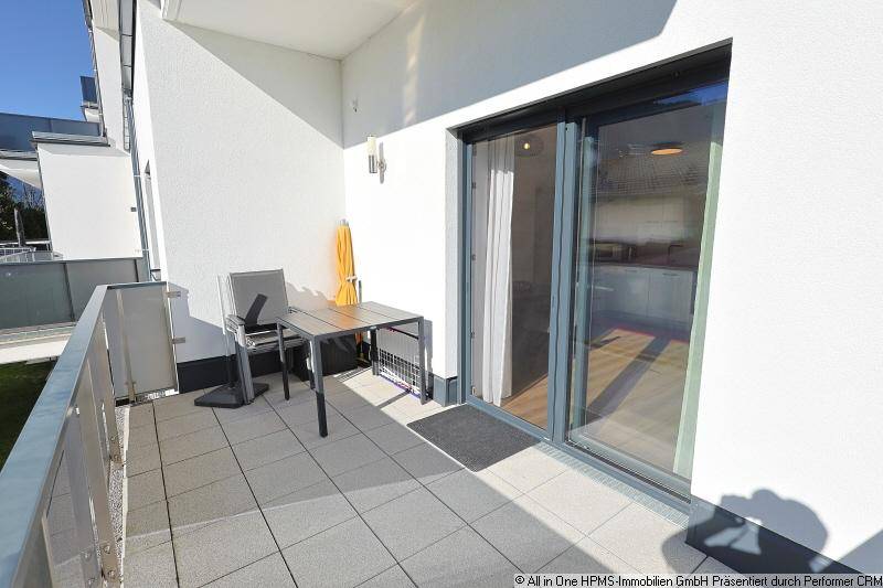 Gemütlicher Balkon mit Fliesenboden, kleinem Tisch und Zugang zum Innenbereich.