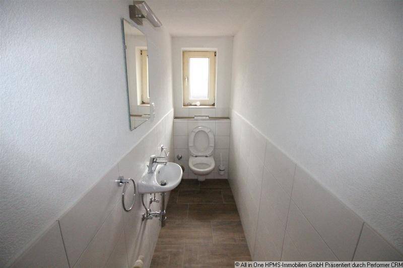Kleines Gäste-WC mit Fenster, wandhängendem WC und modernem Waschbecken.