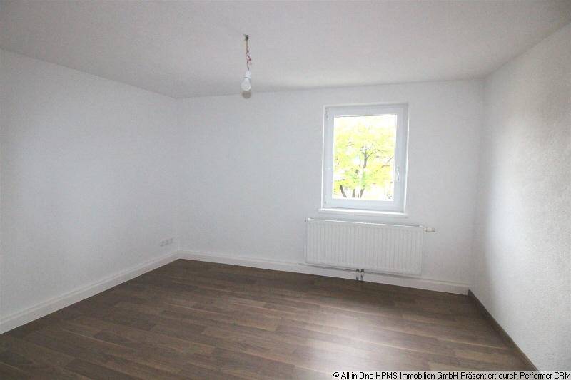 Heller Raum mit Laminatboden, Fenster und Heizkörper, ideal für Schlaf- oder Arbeitszimmer.