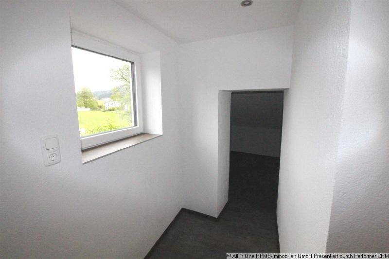 Heller Flurbereich mit großem Fenster und Blick ins Grüne, der viel Tageslicht bietet.