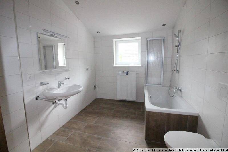 Helles Badezimmer mit Badewanne, Dusche, Waschbecken und Fenster, modern gefliest.