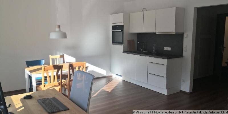 Funktionale Einbauküche mit weißen Schränken, dunkler Arbeitsplatte und integriertem Essbereich.
