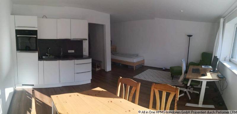 Offener Wohnbereich mit integrierter Küche, Essplatz, Arbeitsbereich und angrenzendem Schlafbereich.