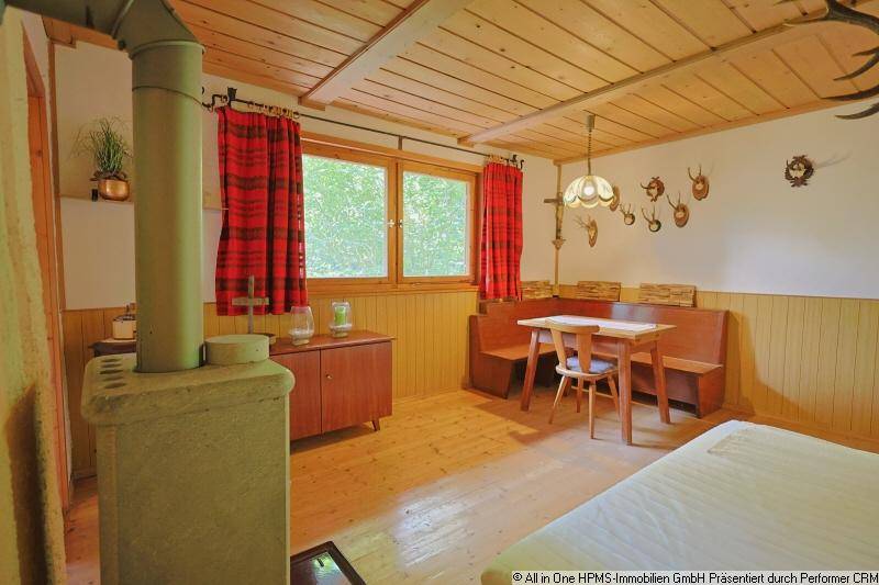 Rustikaler Wohnbereich mit Holzbänken, Esstisch und einem traditionellen Kaminofen.