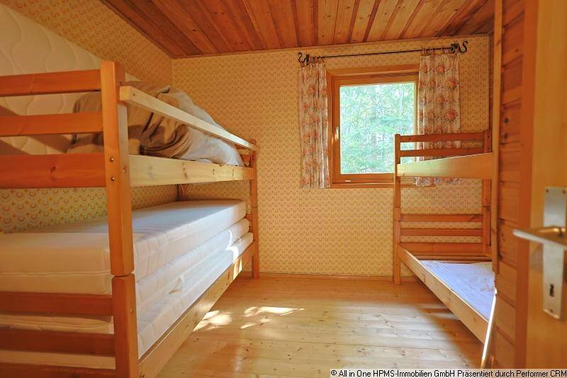 Schlafzimmer mit zwei Etagenbetten, Holzvertäfelung und einem Fenster zur Natur.