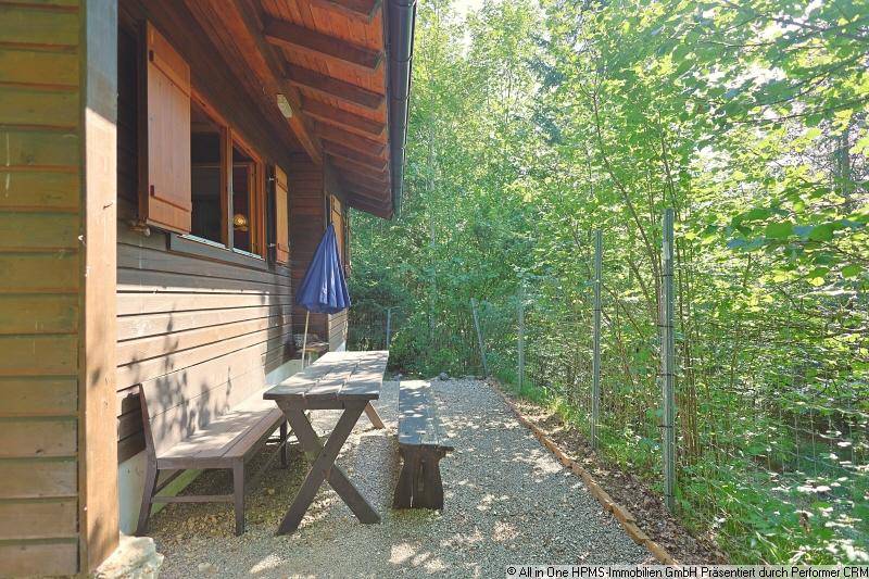 Gemütlicher Sitzbereich im Freien neben der Holzhütte, ideal zum Entspannen in der Natur.
