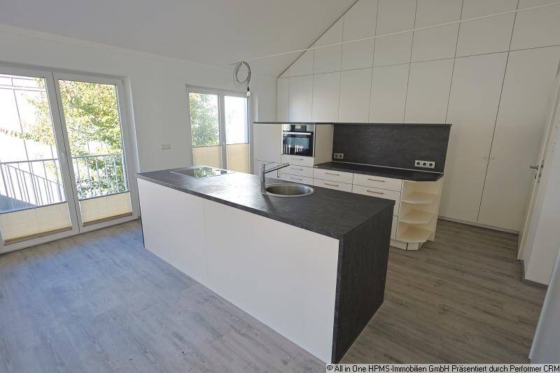 Moderne offene Küche mit Kochinsel, integrierten Geräten und Zugang zu einem Balkon oder einer Terrasse.