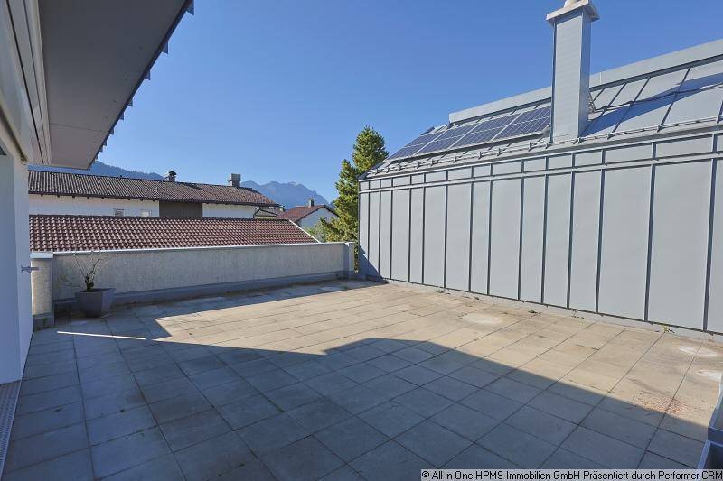 Geräumige Dachterrasse mit Fliesenboden und weitem Blick auf die umliegende Berglandschaft.