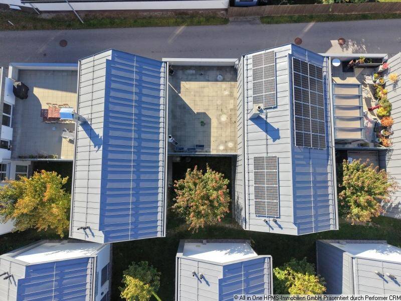 Luftaufnahme moderner Häuser mit grauen Dächern und Solarpaneelen in einer Wohnsiedlung.