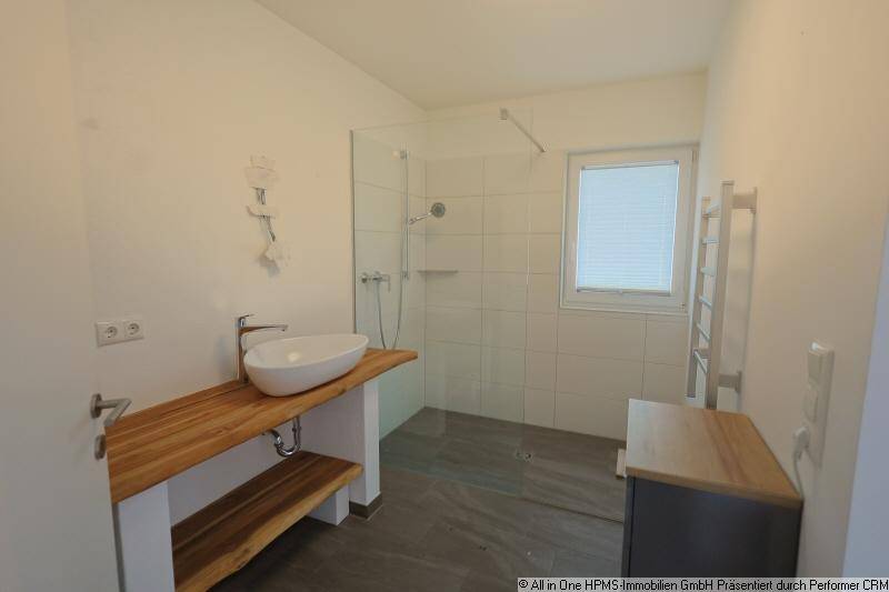 Modernes Badezimmer mit begehbarer Dusche, Holzwaschtisch und beheiztem Handtuchhalter.