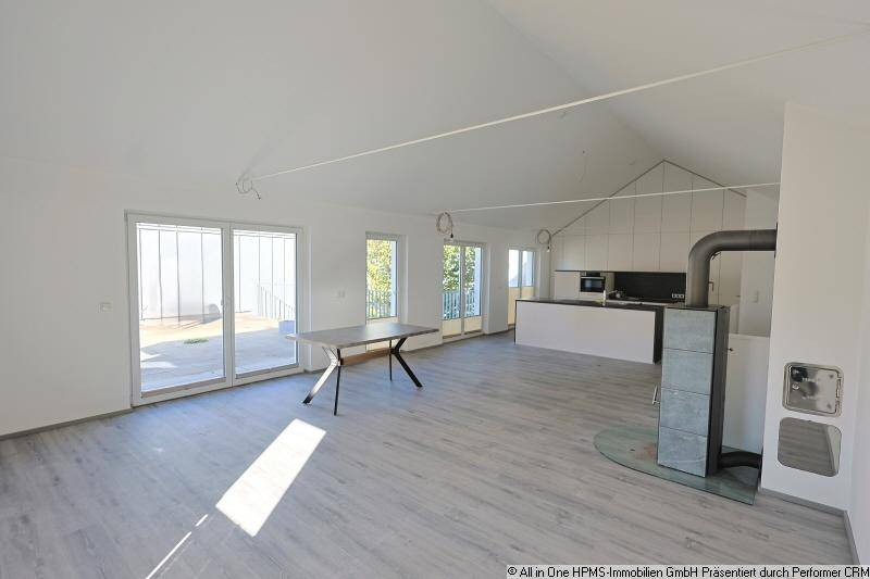 Heller offener Wohn-Essbereich mit modernem Kaminofen, Essbereich und Zugang zur Terrasse.