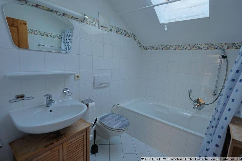 Badezimmer mit Badewanne, Waschbecken, wandhängendem WC und Dachfenster für natürliches Licht.