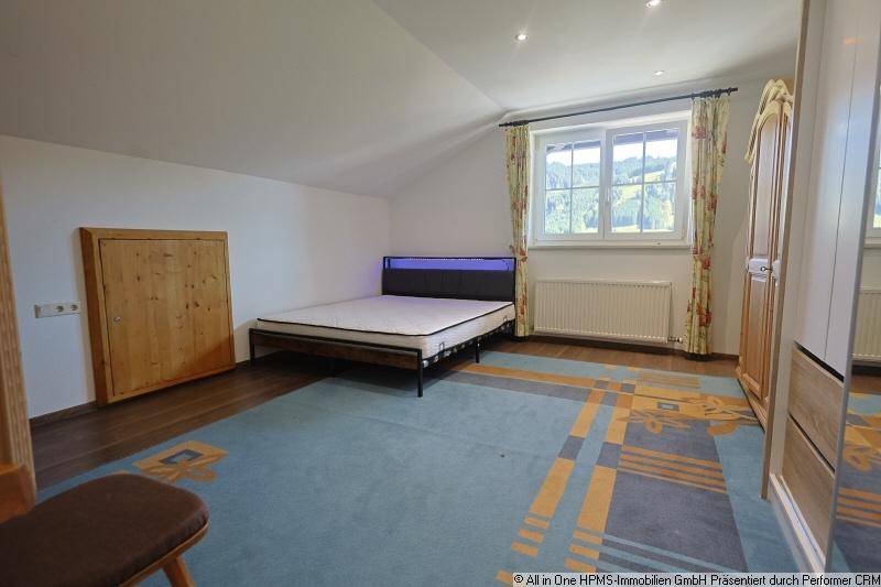 Schlafzimmer mit Laminatboden, Dachschräge, Doppelbett und Blick ins Grüne.