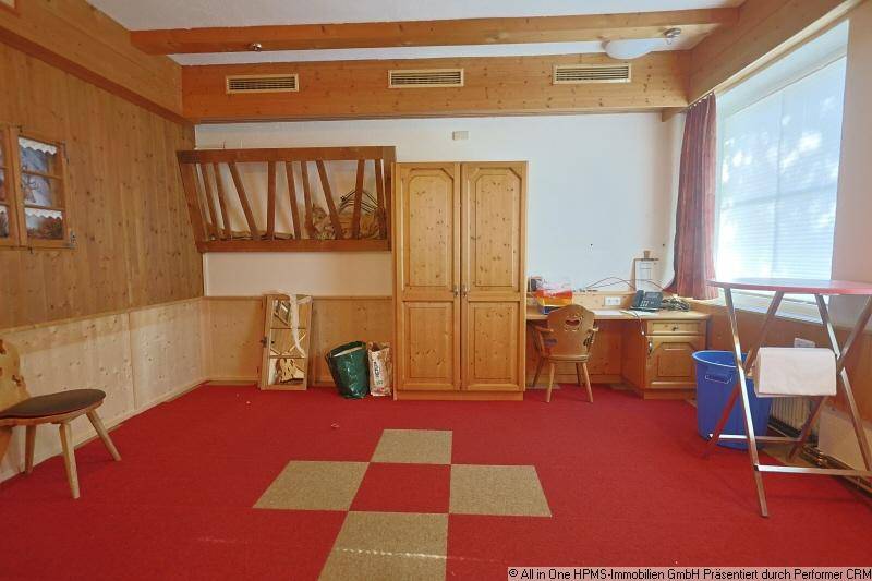 Mehrzweckraum mit rotem Teppichboden, Holztäfelung und traditionellen Holzmöbeln.