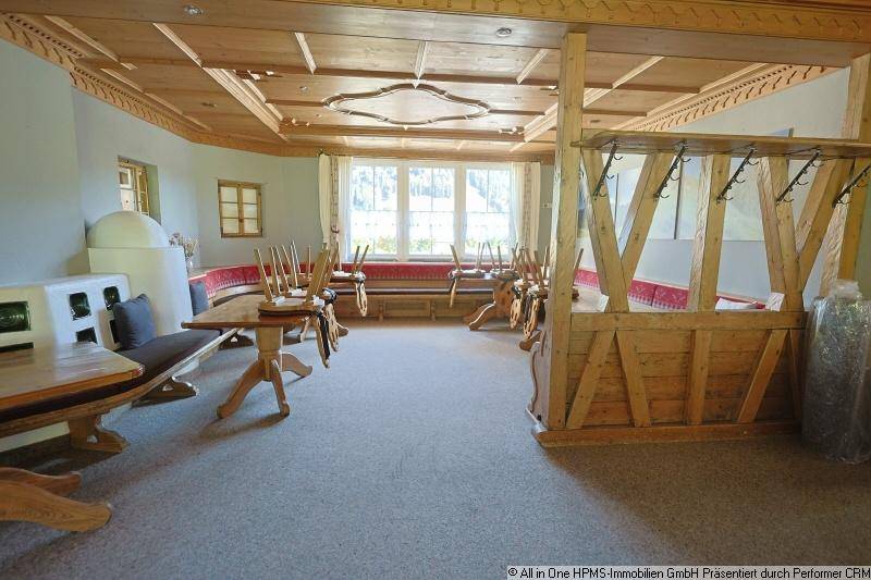 Gemütlicher Speisebereich mit traditionellen Holzmöbeln, Kachelofen und Blick ins Grüne.
