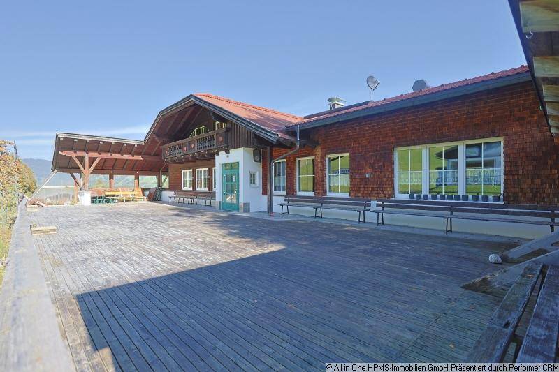Große Holzterrasse vor einem traditionellen Gebäude mit Blick auf die umliegende Landschaft.