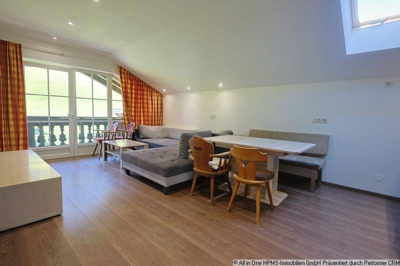 Heller Wohn-Essbereich mit Laminatboden, Dachschräge und Zugang zu einem Balkon.