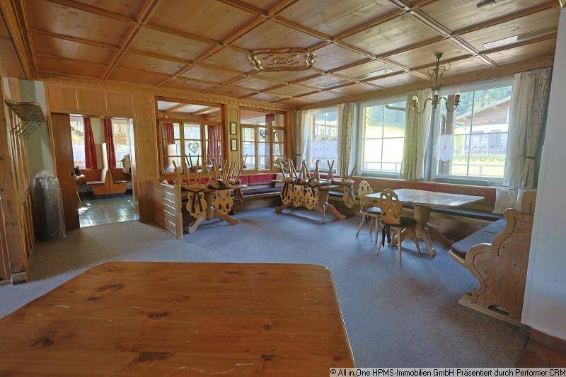 Traditioneller Speisesaal mit Holztäfelung, Kassettendecke und großen Fenstern.