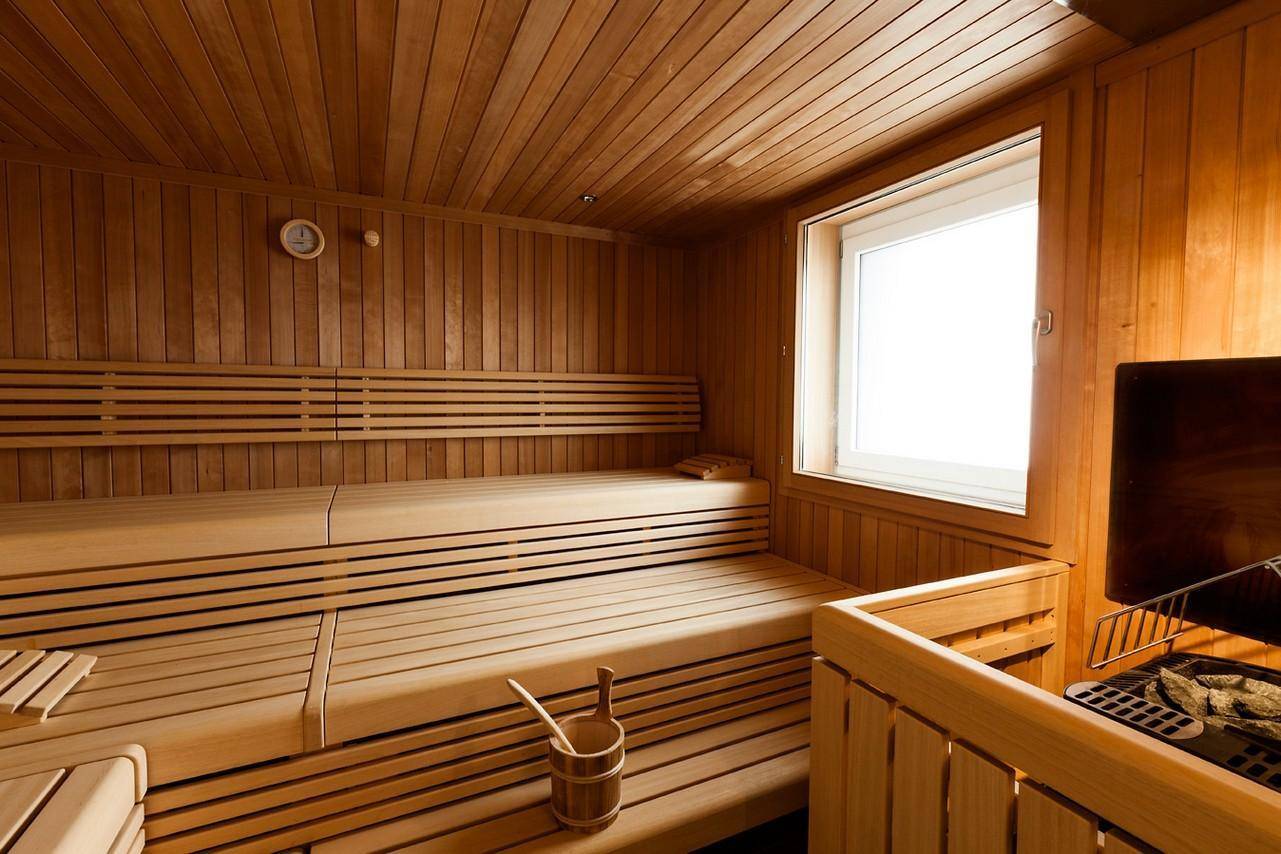 Traditionelle Holzsauna mit mehreren Bänken und einem Fenster für natürliches Licht.