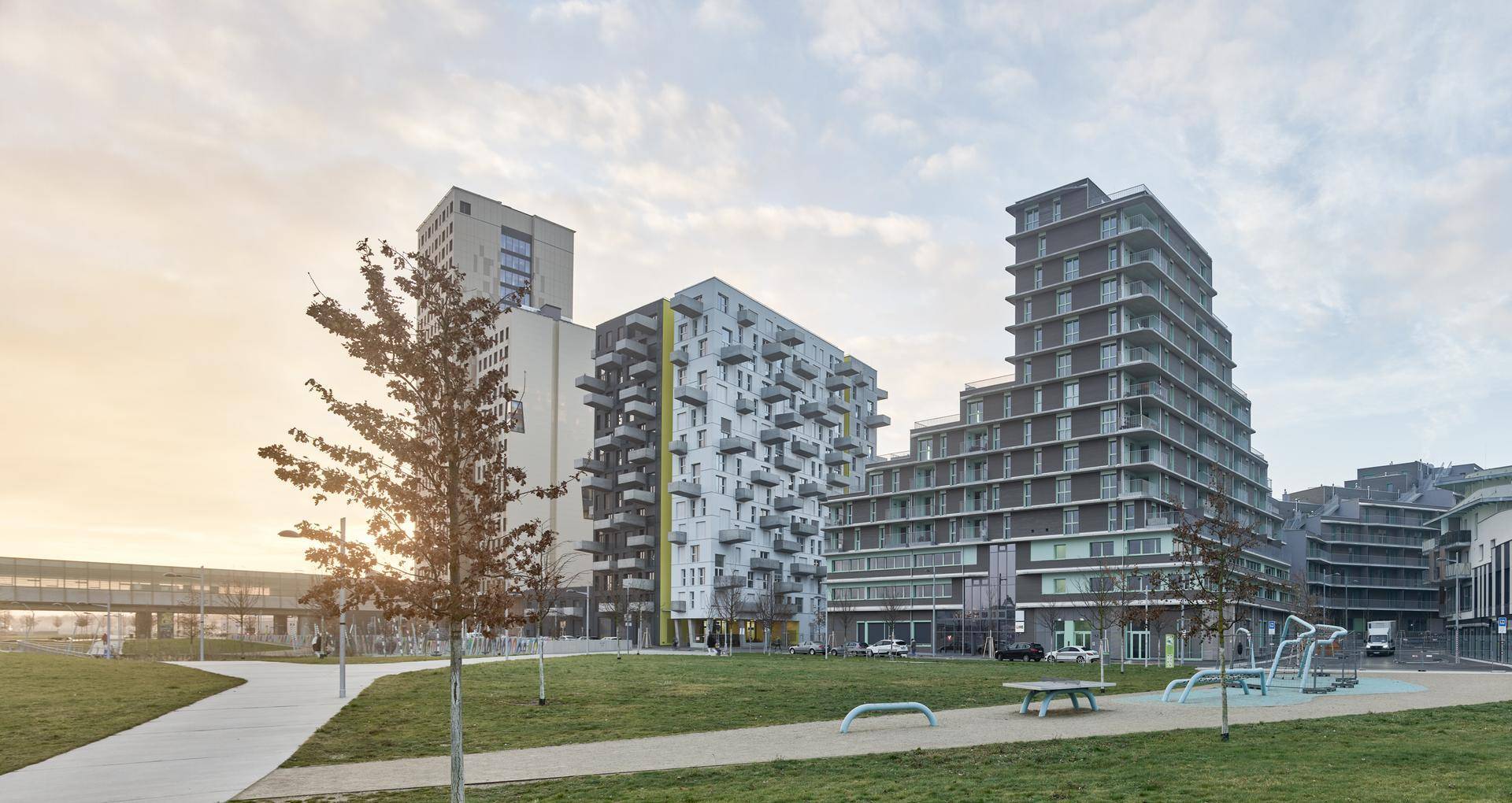 Moderne Wohngebäude in einer städtischen Umgebung mit Grünflächen und Spielgeräten.