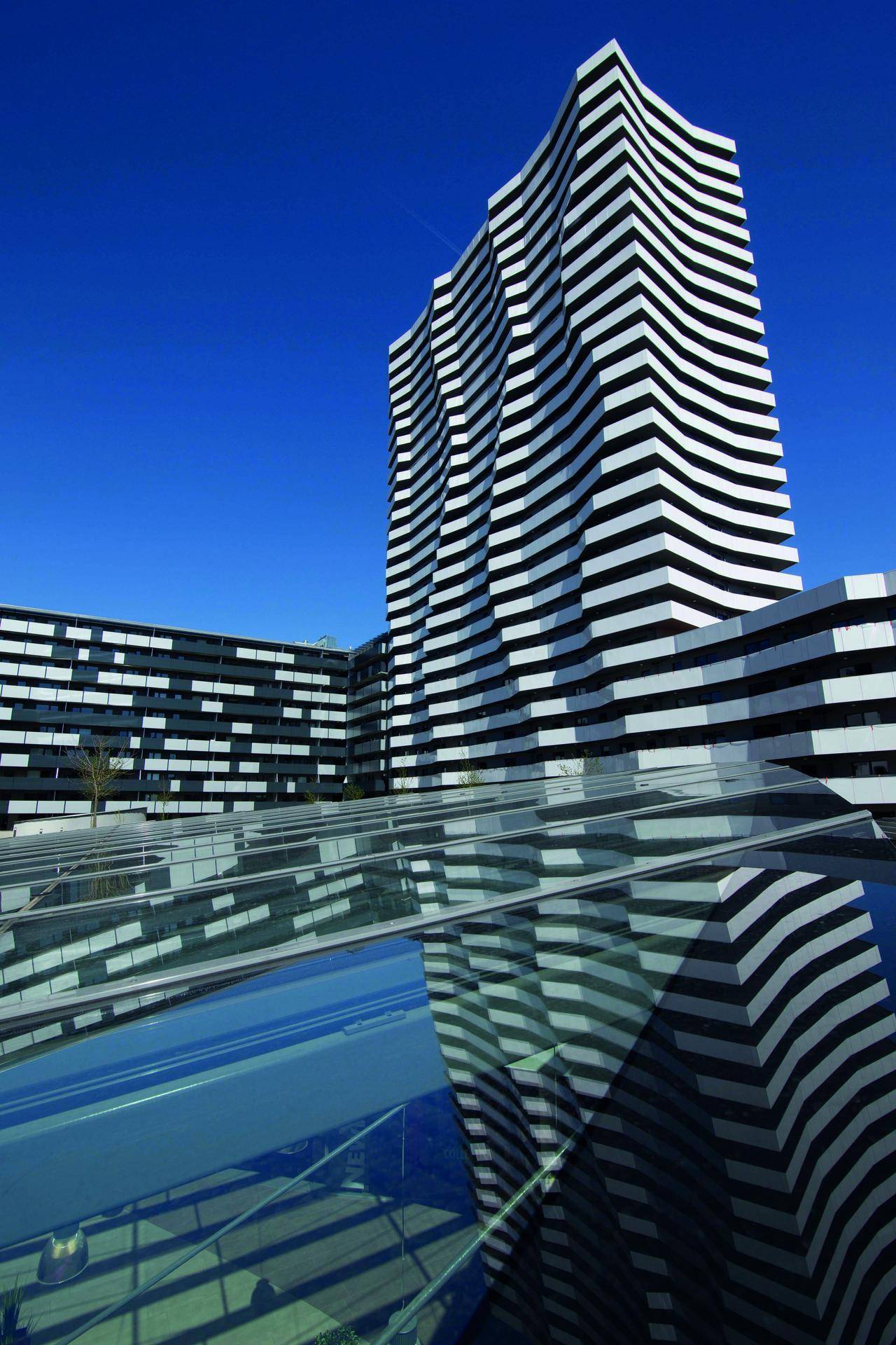 Auffälliges modernes Gebäude mit einer einzigartigen schwarz-weiß gestreiften Wellenfassade unter blauem Himmel.
