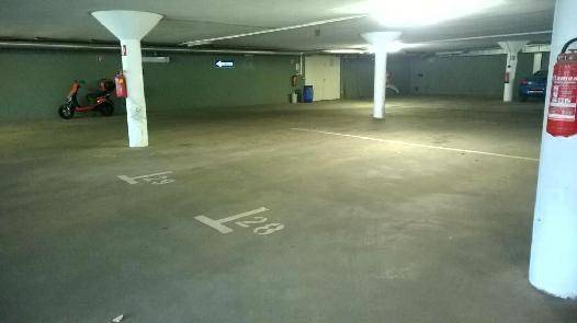 Innenansicht einer Tiefgarage mit nummerierten Stellplätzen, Betonsäulen und Feuerlöscher.
