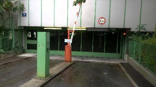 Einfahrt zur Tiefgarage mit Höhenbegrenzung und Schranke, umgeben von Grünflächen.