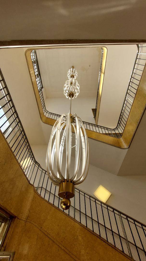 Eindrucksvolles Treppenhaus mit einer großen, dekorativen Hängelampe und goldenen Akzenten.
