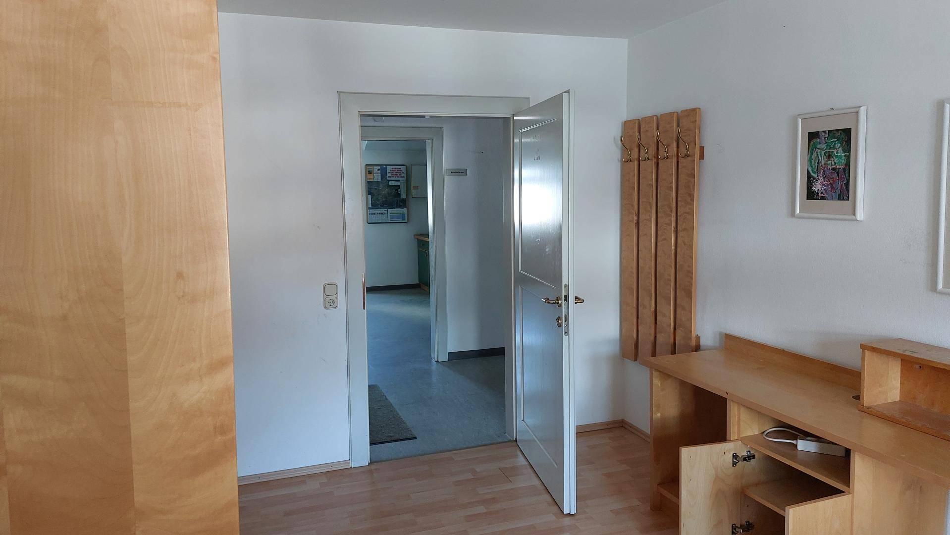 Flur mit Laminatboden und offenen Türen, die den Blick in angrenzende Räume freigeben.