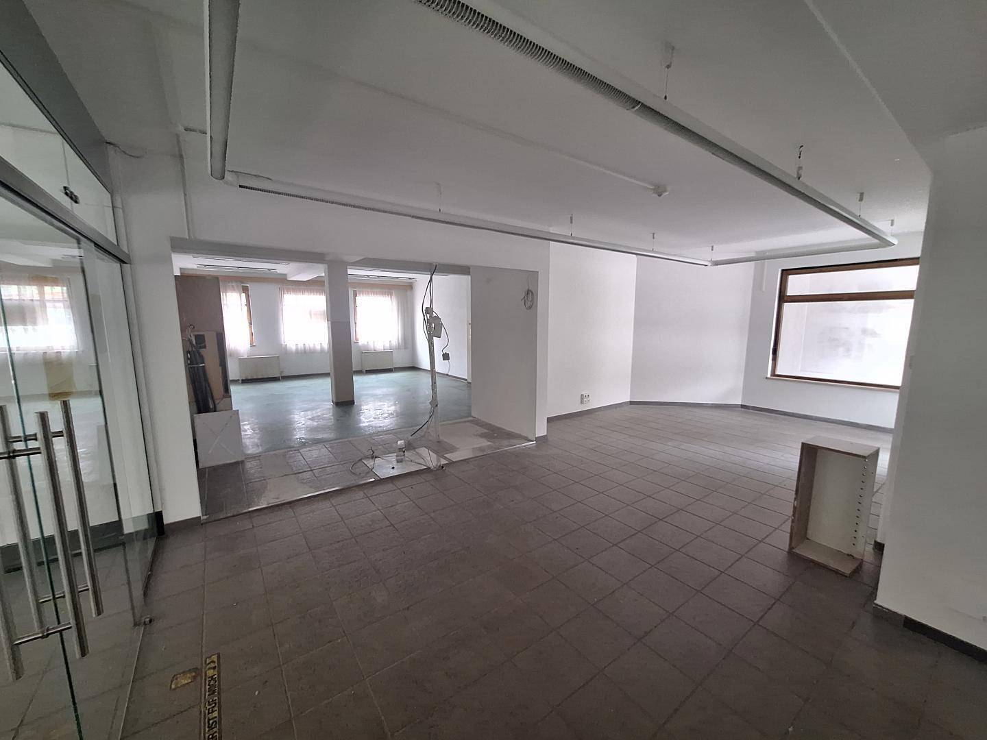 Großer, leerstehender Gewerberaum mit Fliesenboden und großen Fenstern, bereit für den Ausbau.