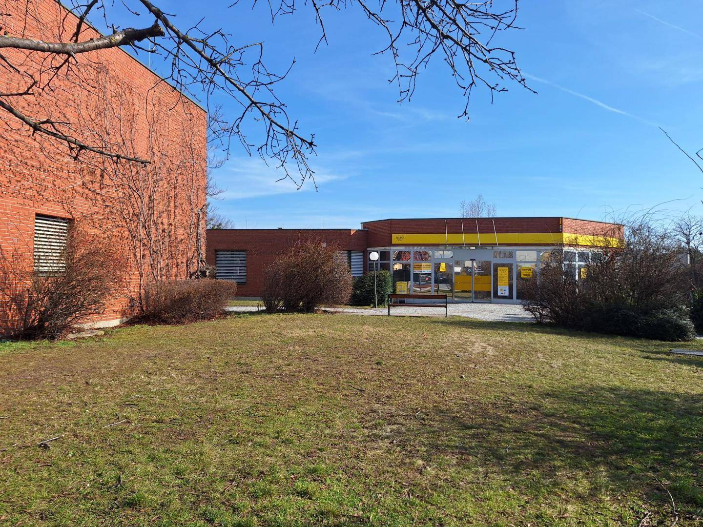 Gebäudeansicht mit einer Rasenfläche im Vordergrund und einem klaren blauen Himmel darüber.