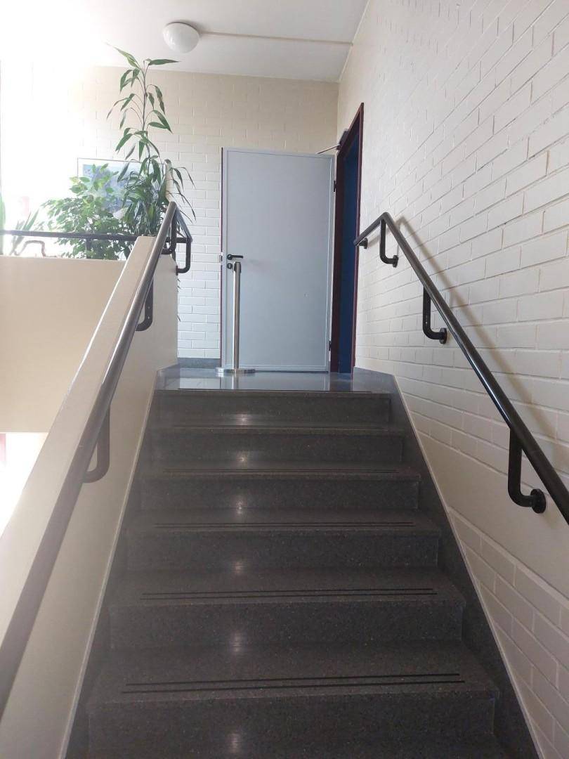 Treppenhaus mit dunklen Granitstufen, weißen Ziegelwänden und stabilen Handläufen.