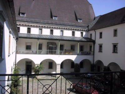 Innenhof eines historischen Gebäudes mit Arkaden, einem Balkon und traditioneller Architektur.