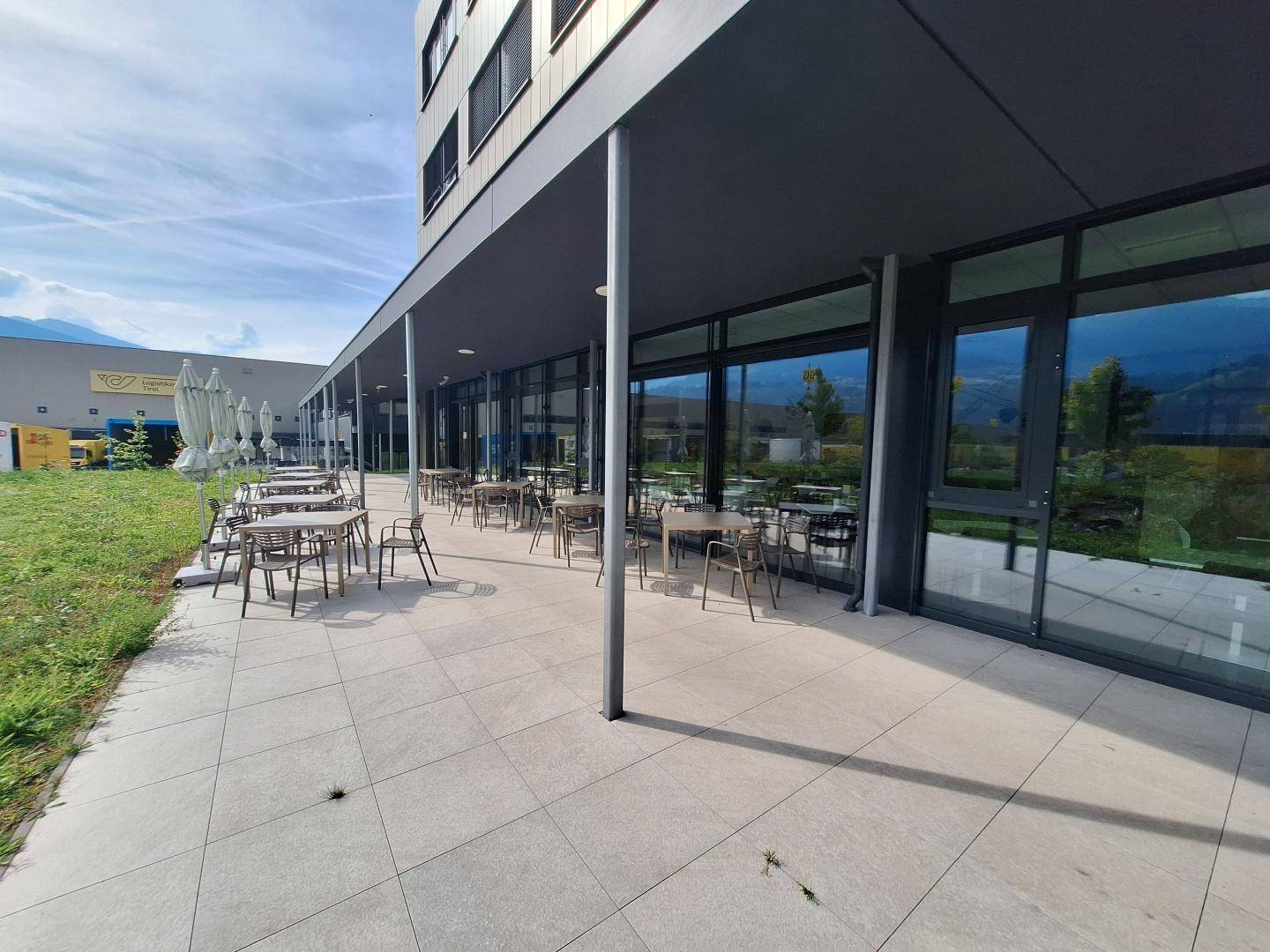 Große Außenterrasse mit Tischen und Stühlen, ideal für Pausen mit Bergblick.