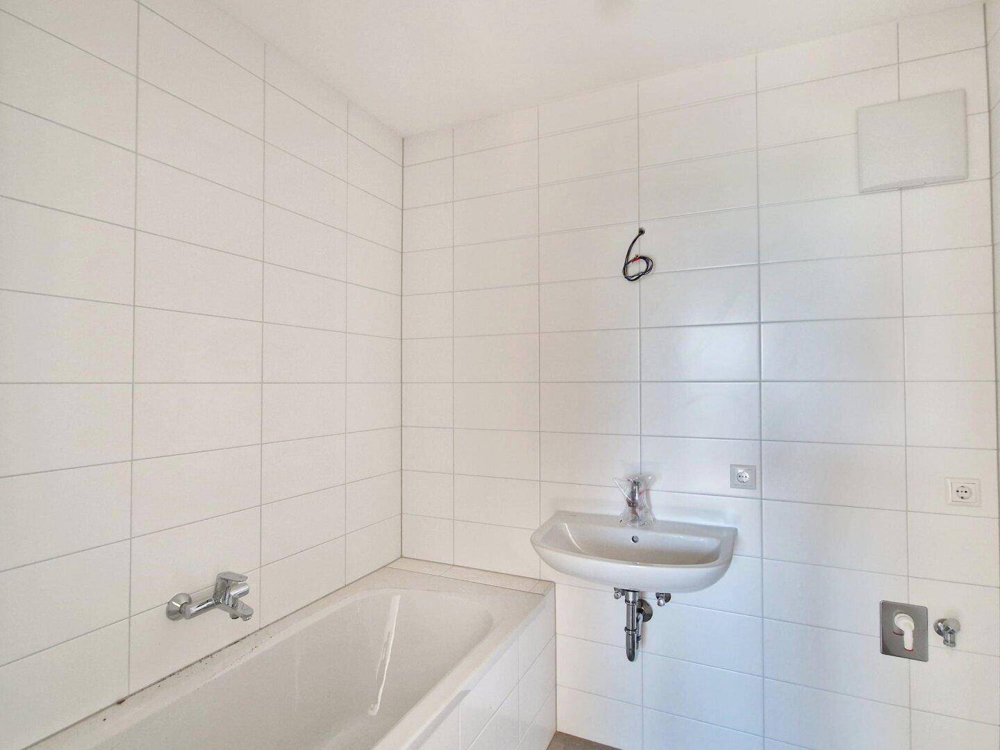 Modern gefliestes Badezimmer mit Badewanne und Waschbecken.