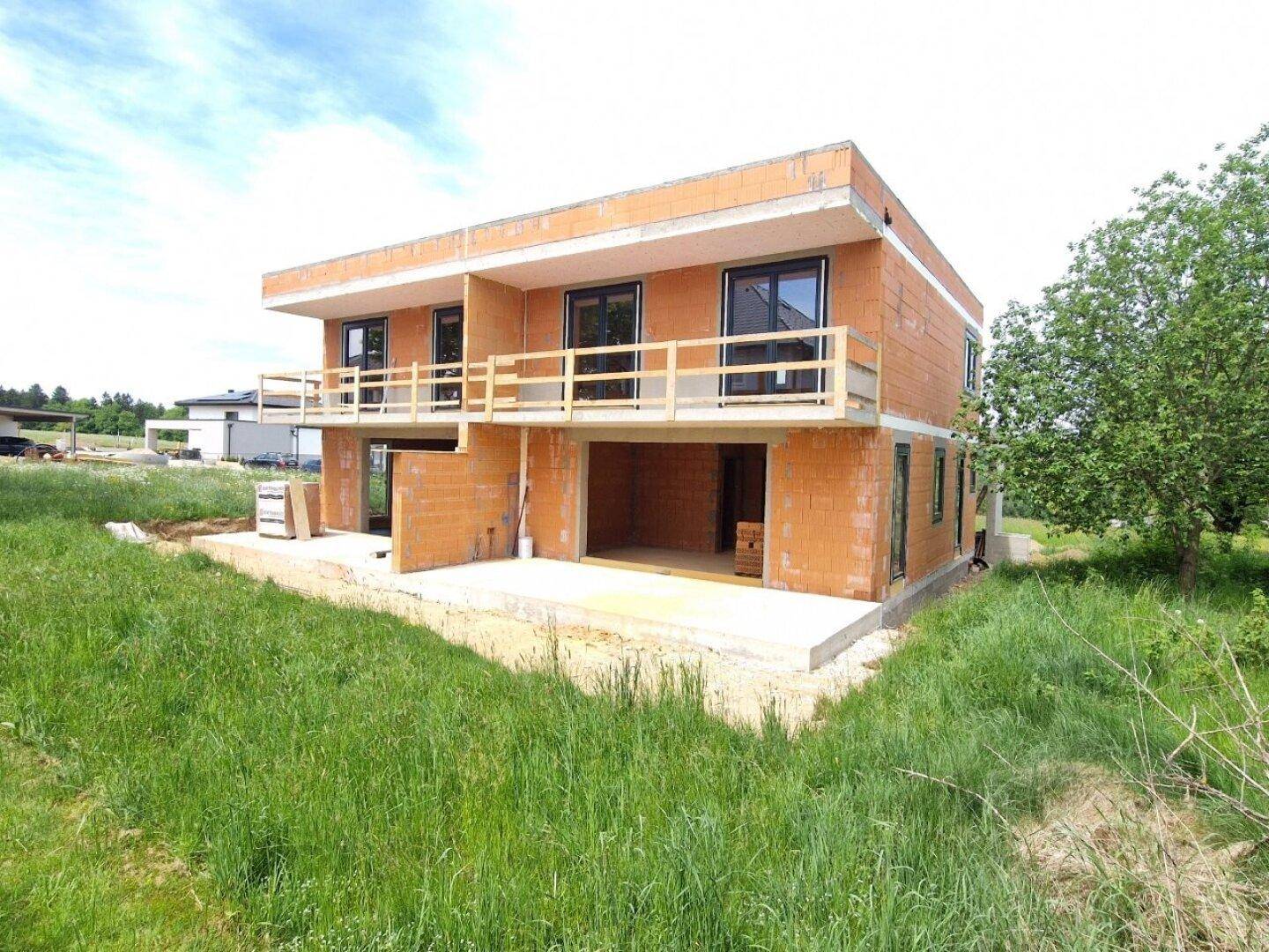 Neubau eines Doppelhauses in Ziegelbauweise mit Balkonen und Fenstern.