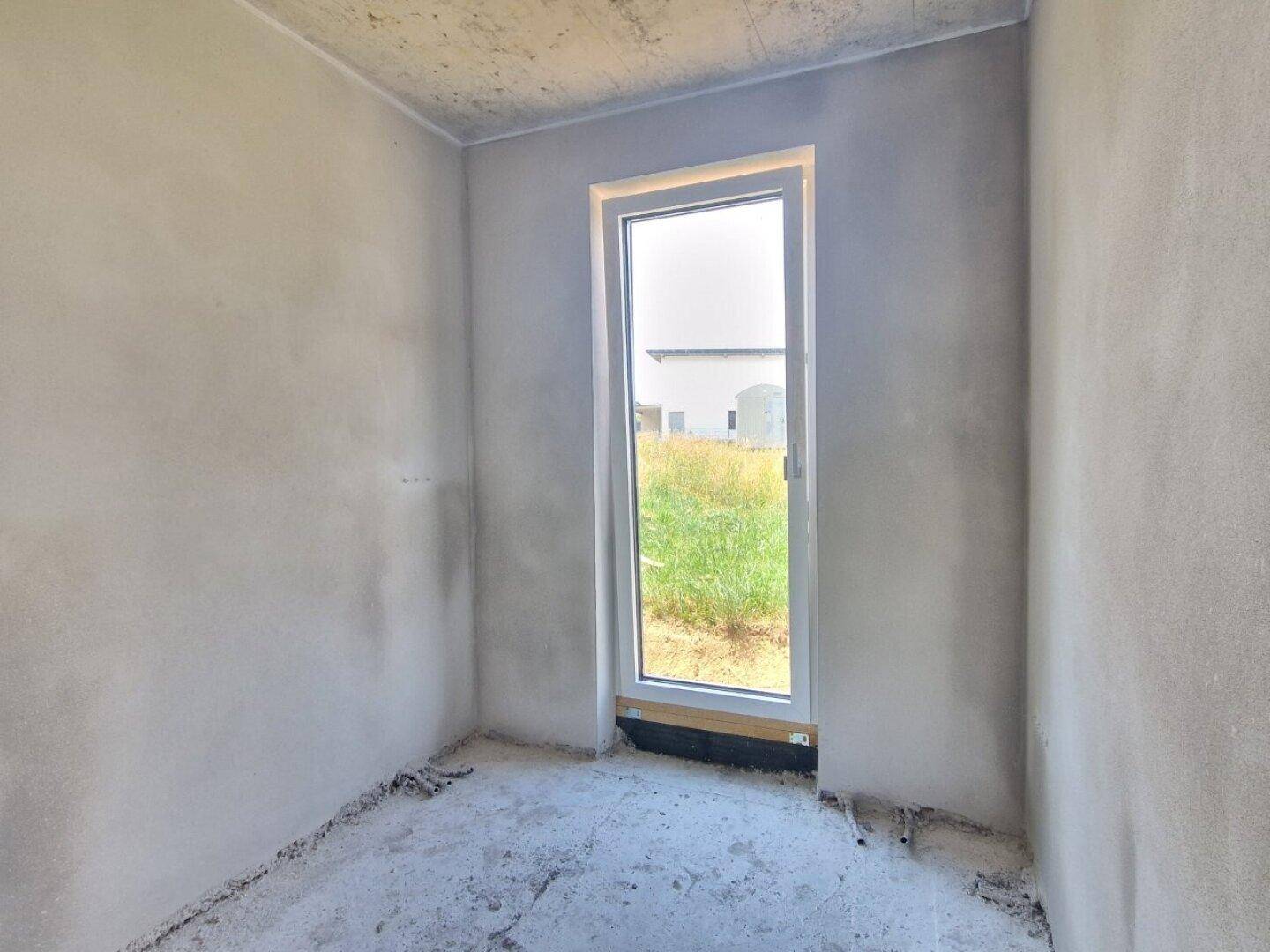 Heller Rohbau-Raum mit Tür zum Außenbereich, bereit für die weitere Gestaltung.