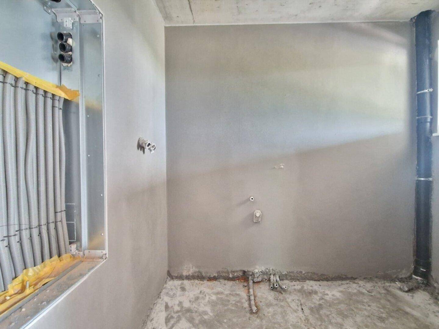 Rohbau-Innenraum mit sichtbaren Installationen und Leitungen, bereit für den weiteren Ausbau.