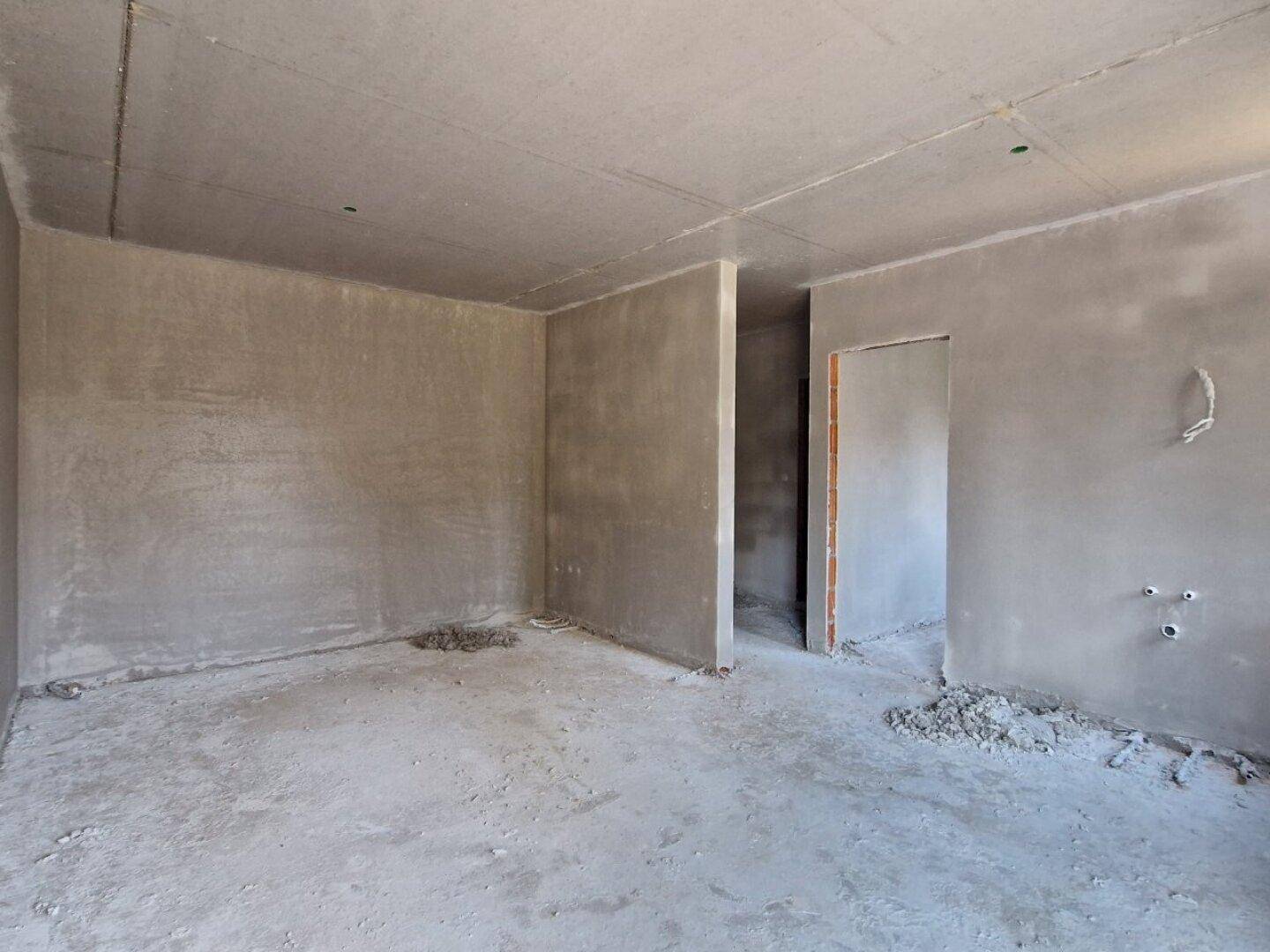Unfertiger Innenraum mit rohen Betonwänden und -boden, bereit für den weiteren Ausbau.