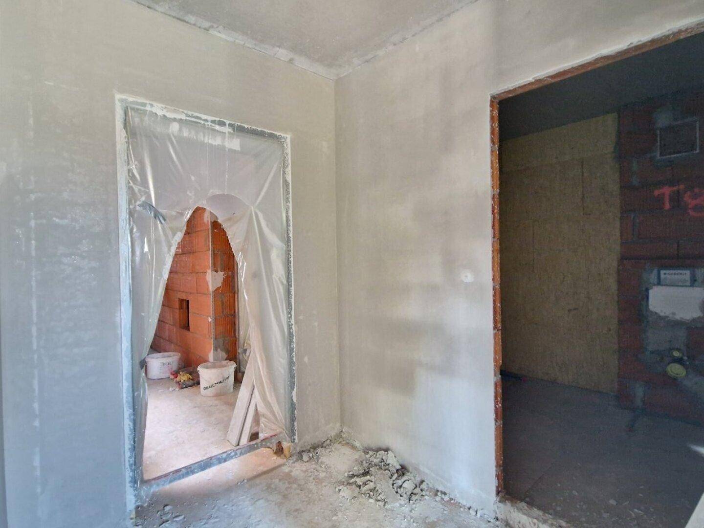 Unfertiger Flurbereich mit Türöffnungen, die in weitere Räume des Rohbaus führen.