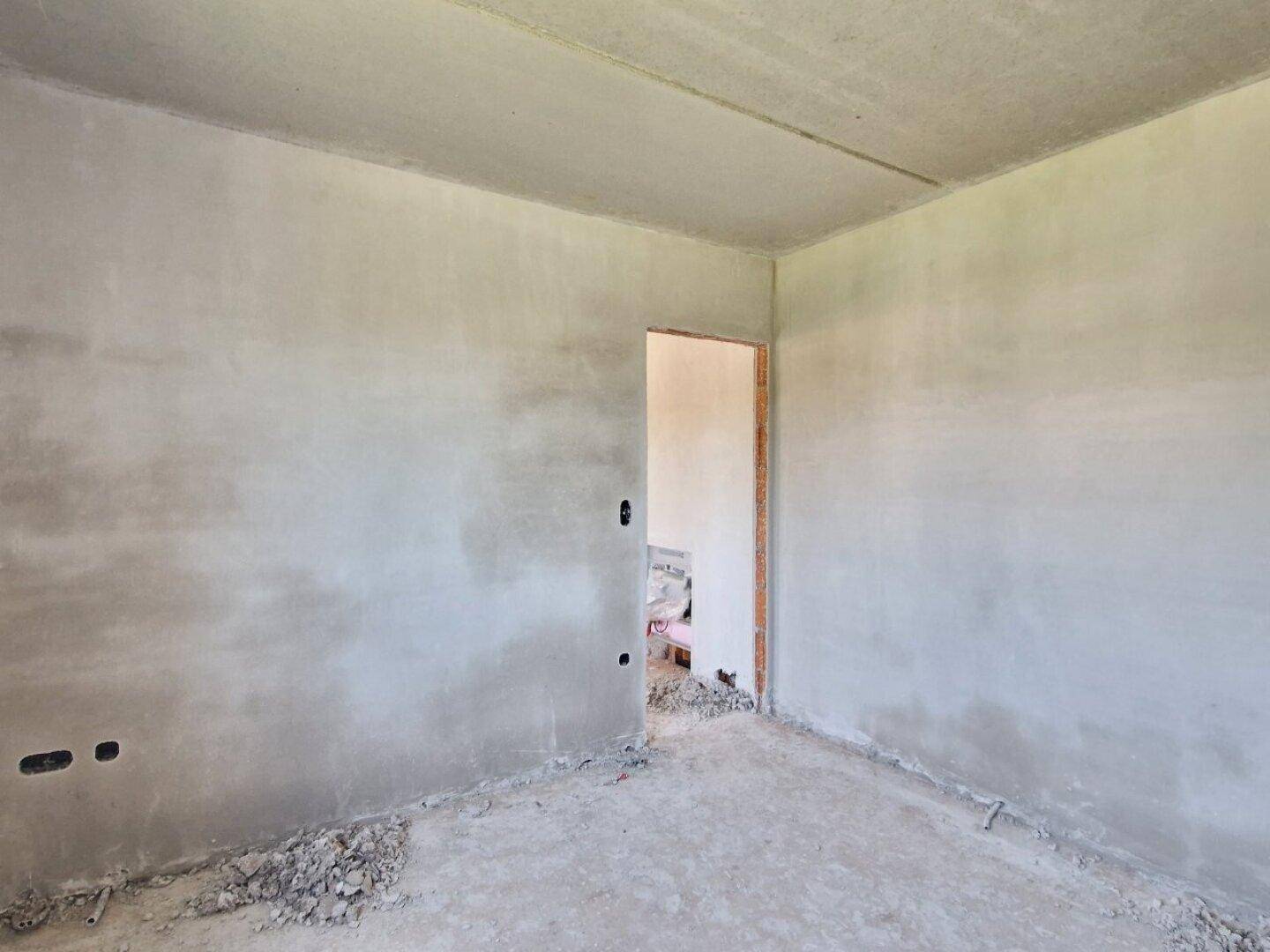 Unfertiger Raum im Neubau mit einer Türöffnung und rohen Wänden, bereit für den Ausbau.