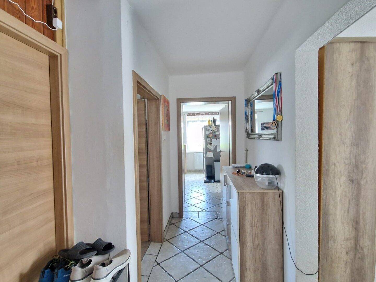 Heller Flur mit Fliesenboden und Holztüren, der zu weiteren Räumen führt.