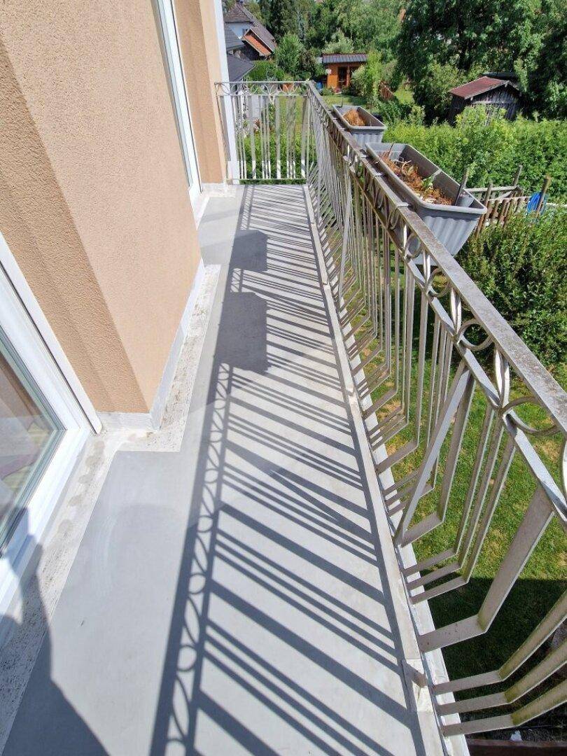 Langer, schmaler Balkon mit Metallgeländer und Blick ins Grüne.