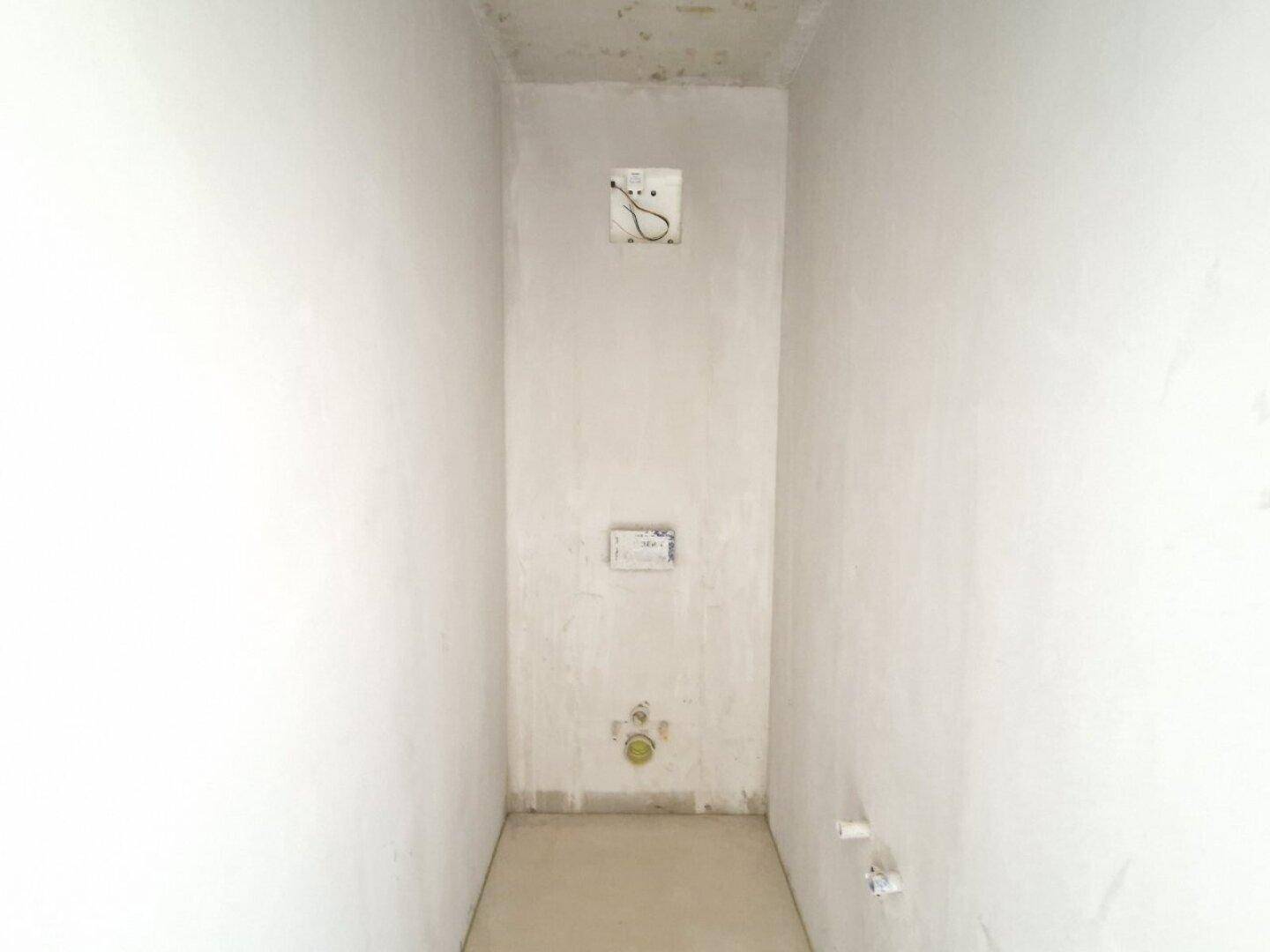 Kleiner Raum im Rohbau, vorbereitet für ein WC oder Gäste-WC mit sichtbaren Anschlüssen.